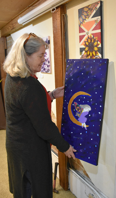 Cynthia Miller hanging a painting